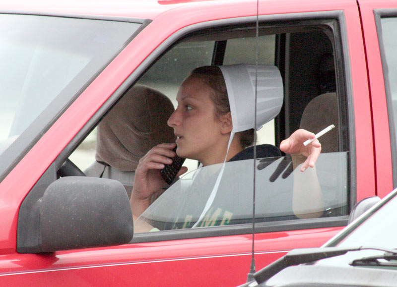 amish woman smoking cigarette while on the cell phone