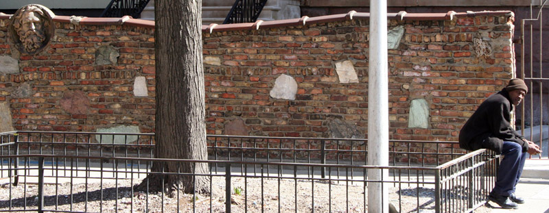 Man sitting near sculpture of a relief of a face.